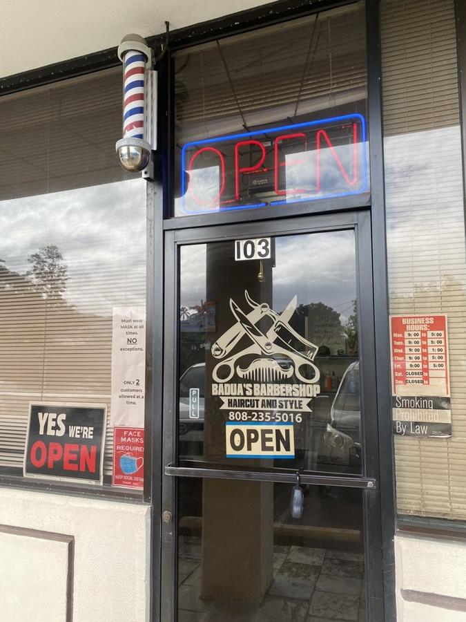 Barber pole and hours sign by the door